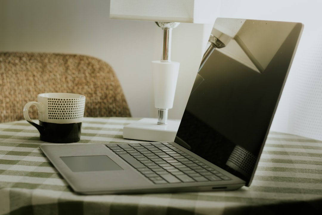 Laptop and coffee cup on a checkered tablecloth.