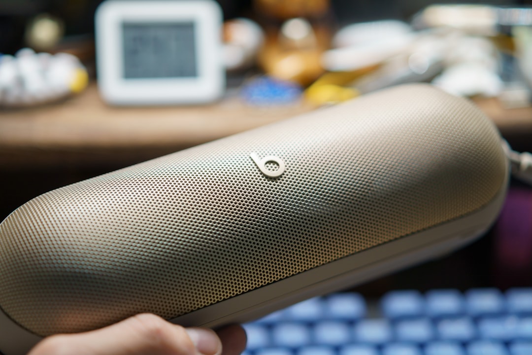 A hand holding a gold beats pill speaker.