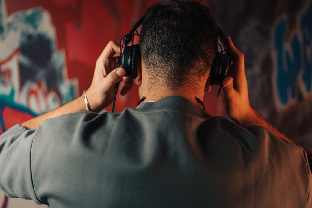 Man adjusting headphones with graffiti wall behind