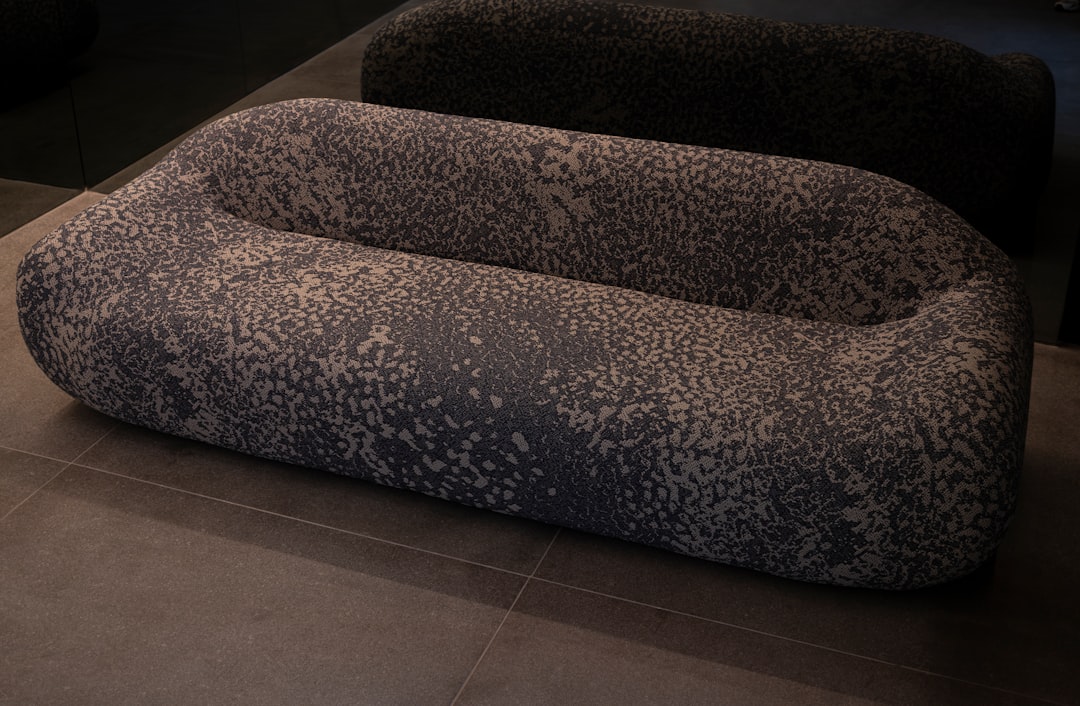 A uniquely shaped, patterned sofa on a tiled floor.