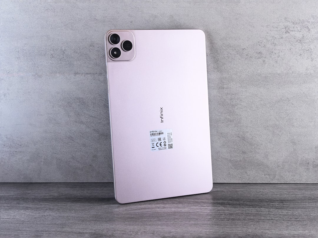 Pink tablet with triple camera system on gray background.