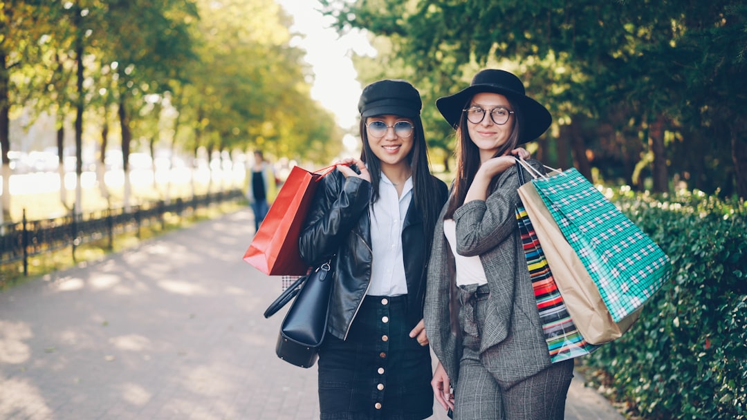 Two women with shopping bags in a park.