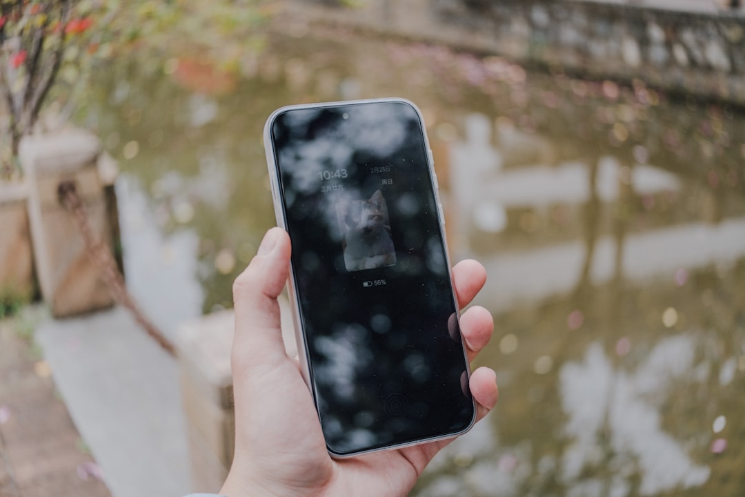 A hand holding a smartphone with reflection.